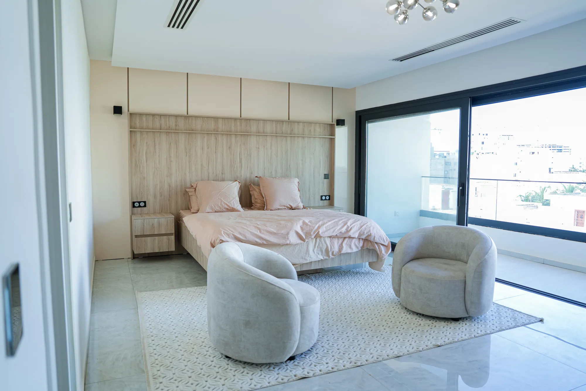 Chambre principale, fauteuils et baie sur la ville