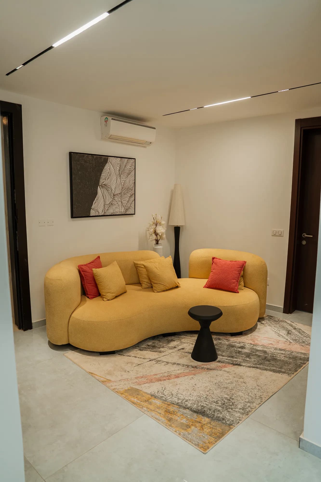 Studio meublé, canapé courbe jaune et tapis terre