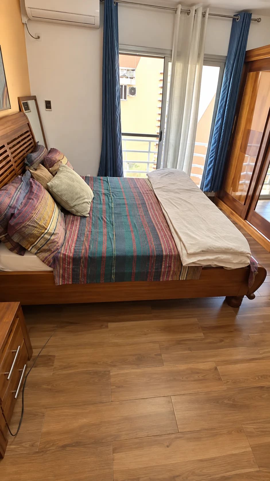 Chambre principale, lit en bois et rideaux bleus